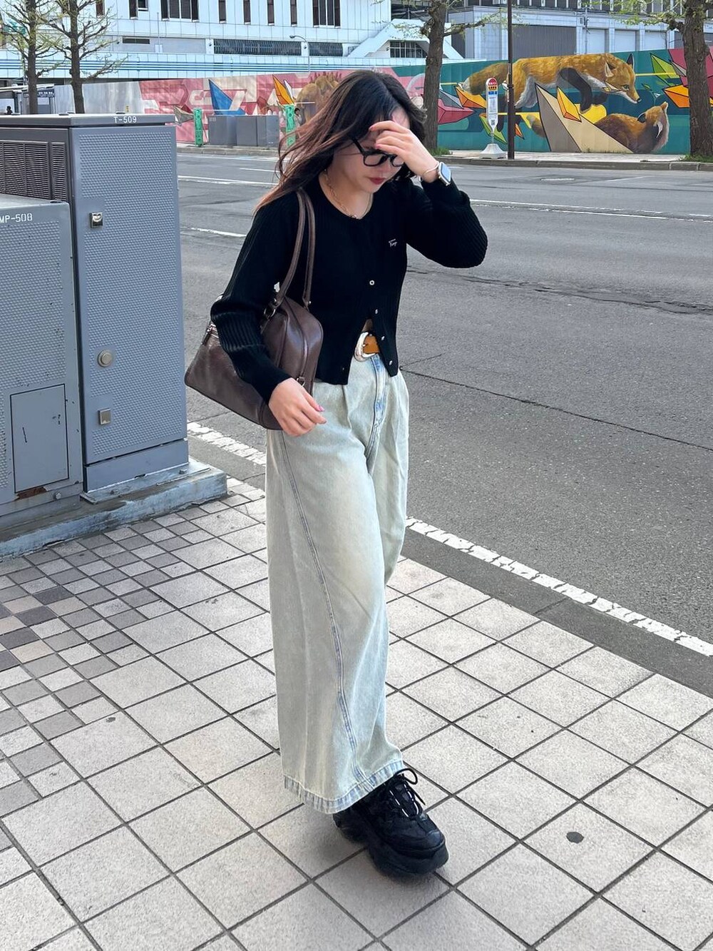 ブラック系のスニーカー、ブルー系のデニムパンツ、ブラウン系のボストンバッグを着用したレディースの夏コーディネートの7枚目の写真