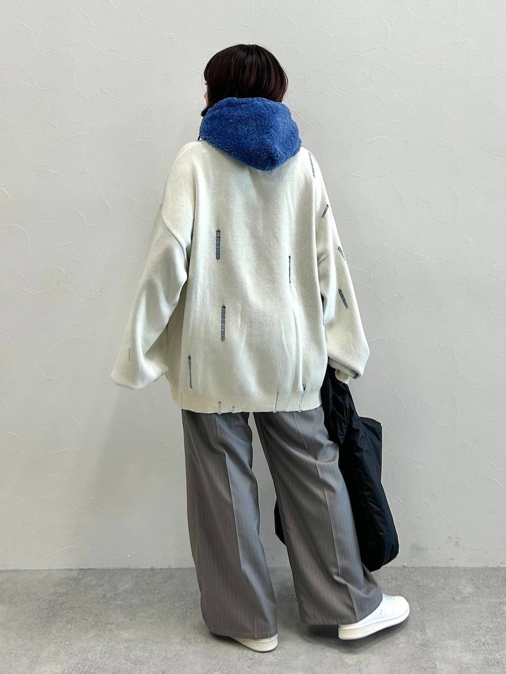 グレー系のスラックス、ホワイト系のニット/セーター、ブラック系のトートバッグを着用したレディースの秋コーディネートの5枚目の写真