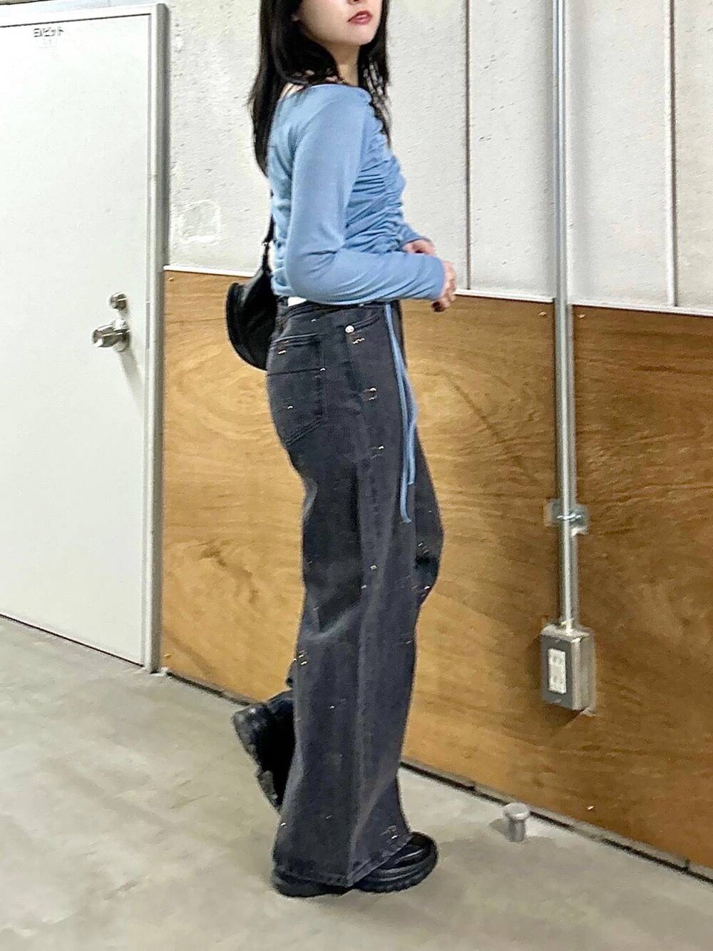 ブラック系のデニムパンツ、ブラック系のスニーカー、ブラック系のショルダーバッグを着用したレディースの春コーディネートの6枚目の写真