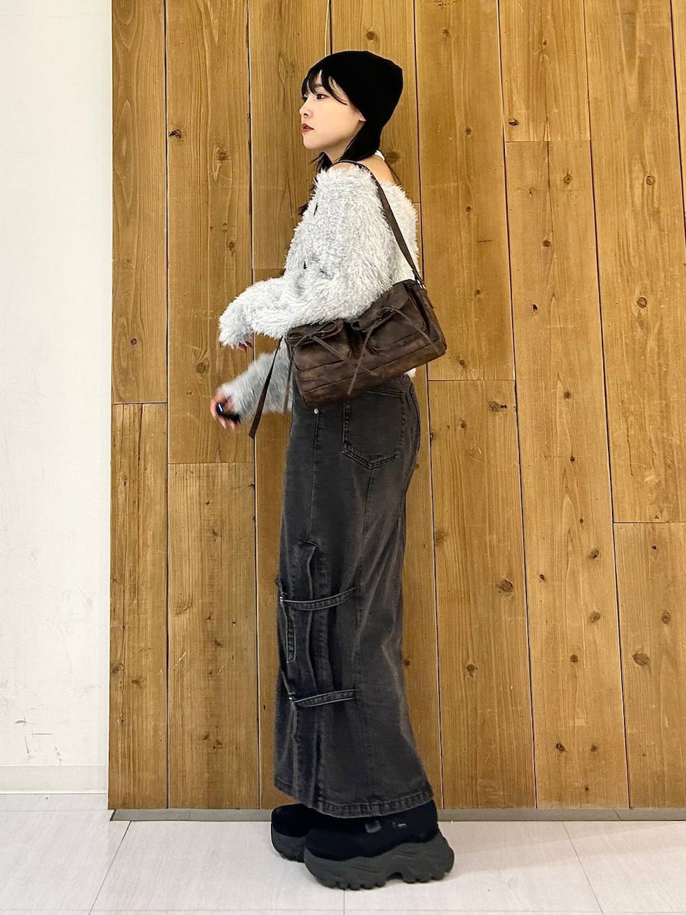 ブラウン系のショルダーバッグ、ブラック系のデニムスカート、ブラック系のスニーカーを着用したレディースの秋コーディネートの4枚目の写真