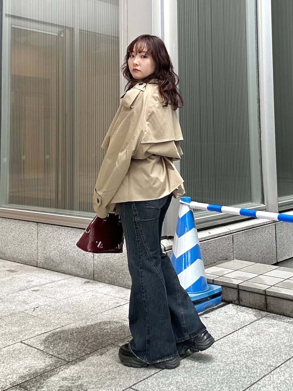 ブラック系のスニーカー、ブルー系のデニムパンツ、ベージュ系のトレンチコートを着用したレディースの秋コーディネートの3枚目の写真