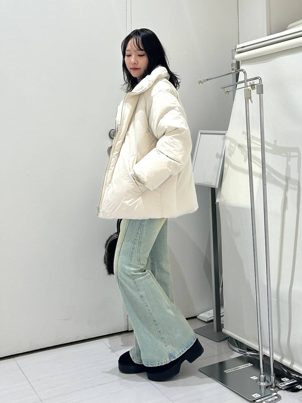 ブルー系のデニムパンツ、ホワイト系のブルゾン、ブラック系のブーツを着用したレディースの冬コーディネートの2枚目の写真