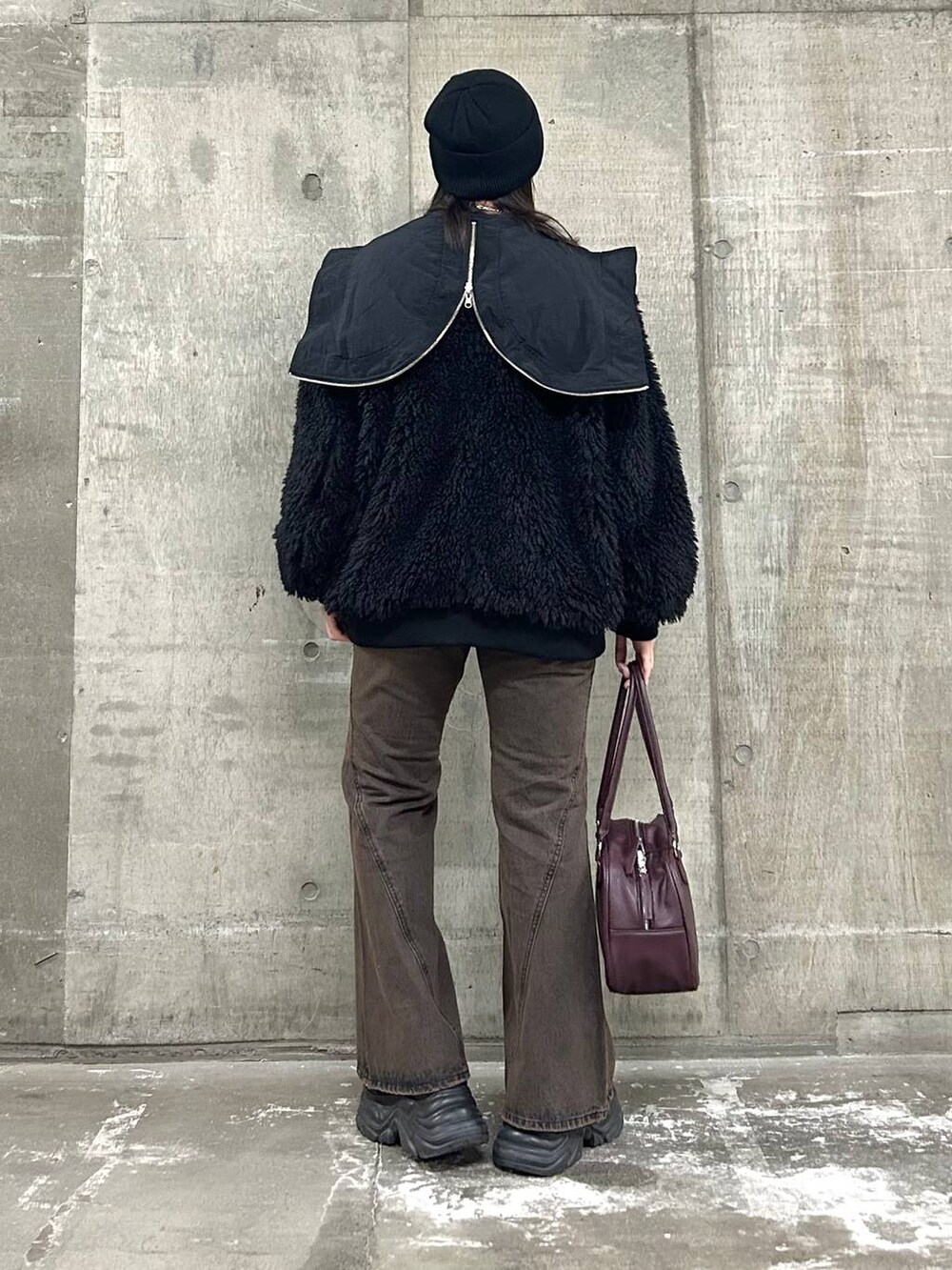 ブラウン系のデニムパンツ、ブラック系のブルゾン、ブラック系のボストンバッグを着用したレディースの秋コーディネートの5枚目の写真