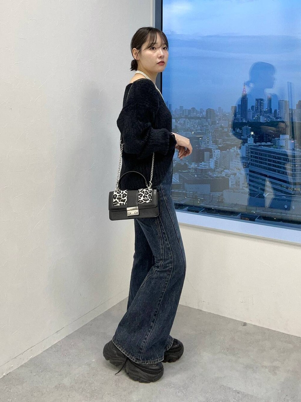 ブラック系のスニーカー、ブルー系のデニムパンツ、ブラック系のニット/セーターを着用したレディースの秋コーディネートの4枚目の写真