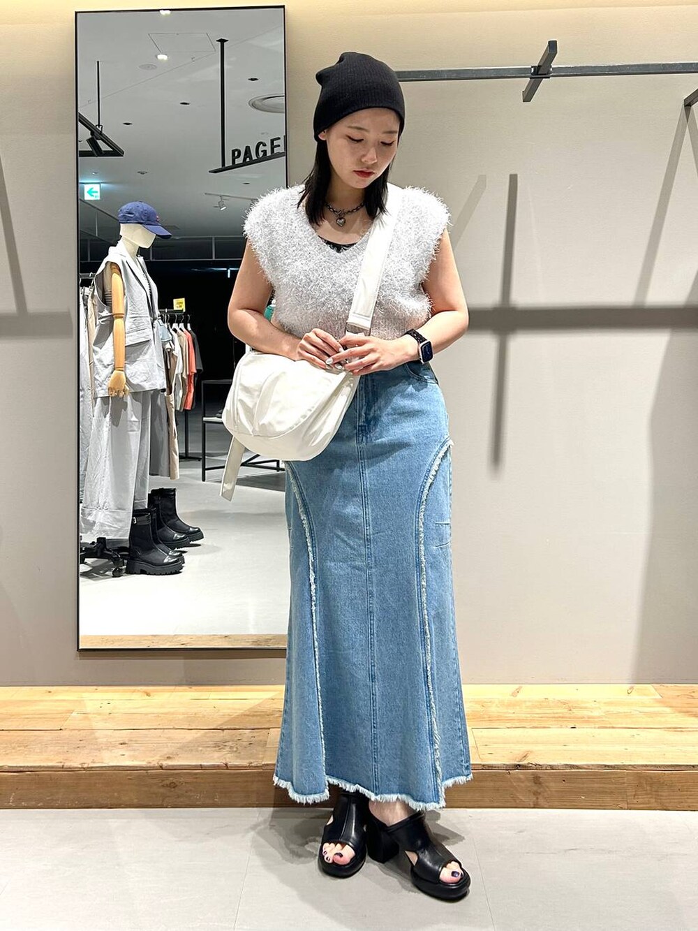 ホワイト系のベスト、ブルー系のデニムスカート、ブラック系のネックレスを着用したレディースの夏コーディネートの4枚目の写真