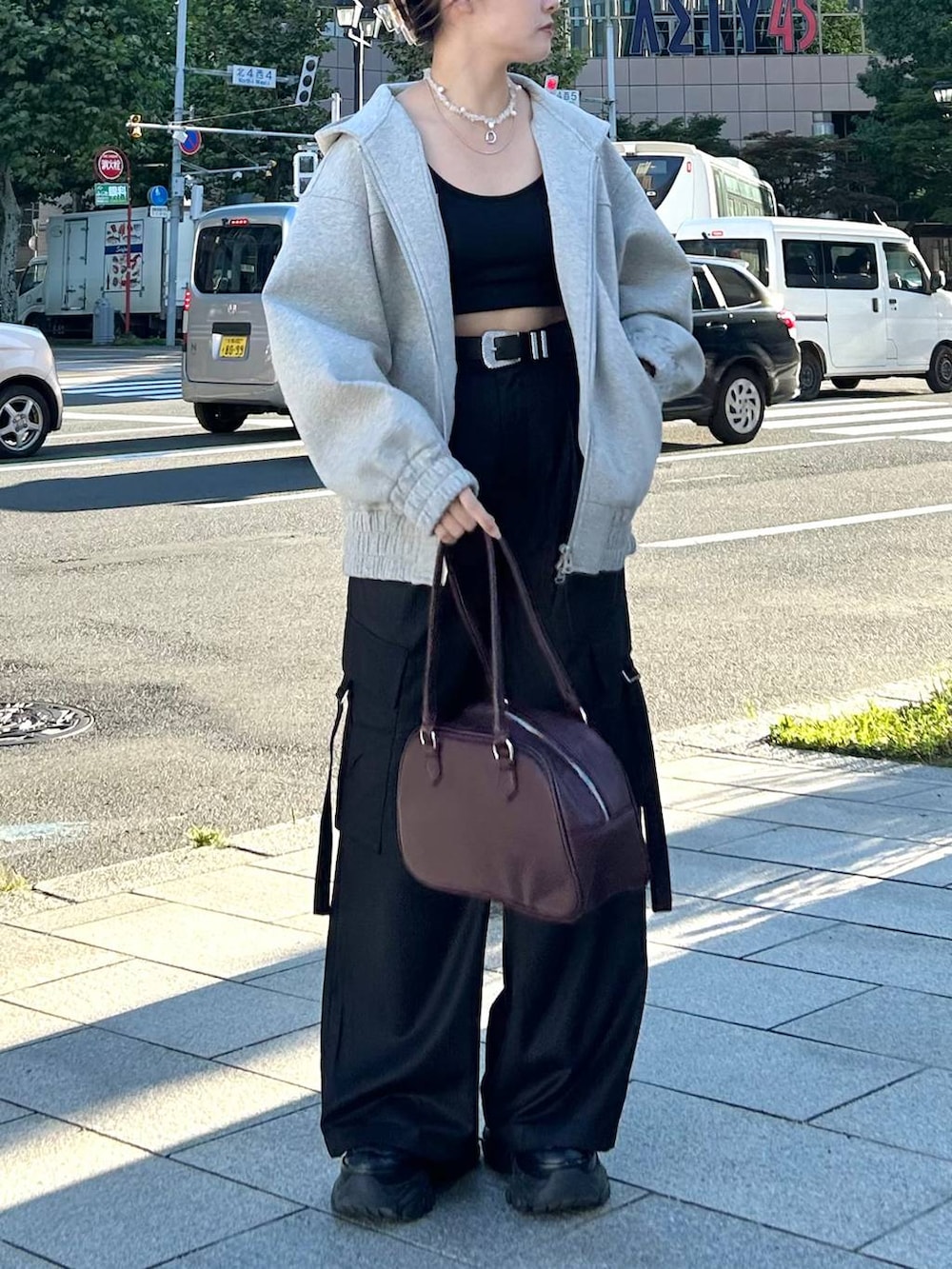 グレー系のパーカー、レッド系のボストンバッグ、ブラック系のスラックスを着用したレディースの秋コーディネートの4枚目の写真