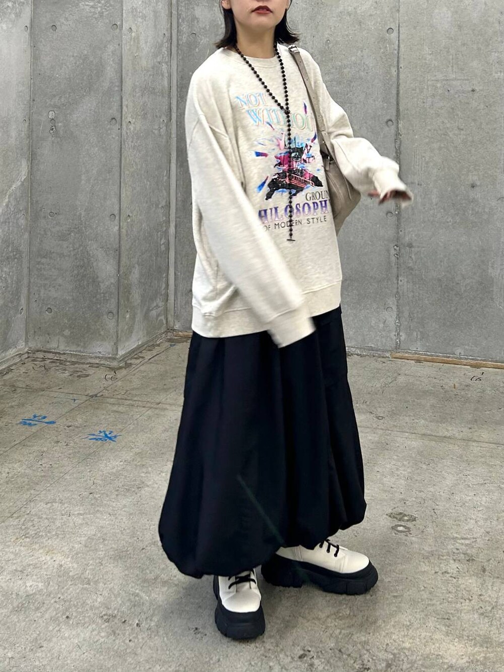 ベージュ系のスウェット、ベージュ系のボストンバッグ、ホワイト系のブーツを着用したレディースの冬コーディネートの3枚目の写真