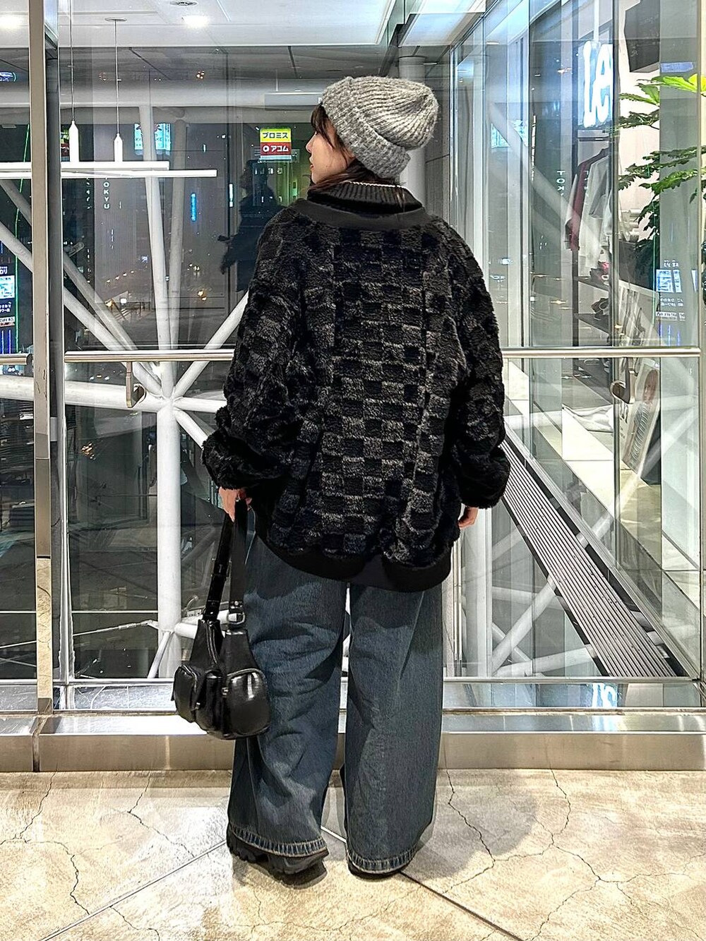 ブルー系のデニムパンツ、ブラック系のブルゾン、ブラック系のショルダーバッグを着用したレディースの秋コーディネートの4枚目の写真