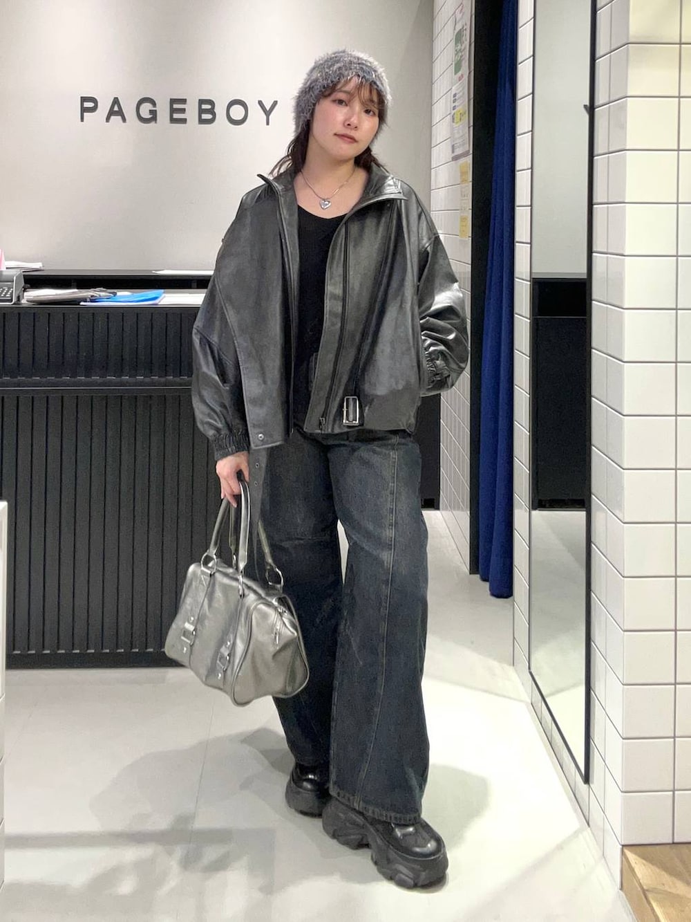 ブルー系のデニムパンツ、ブラック系のスニーカー、ブラック系のライダースジャケットを着用したレディースの秋コーディネートの2枚目の写真