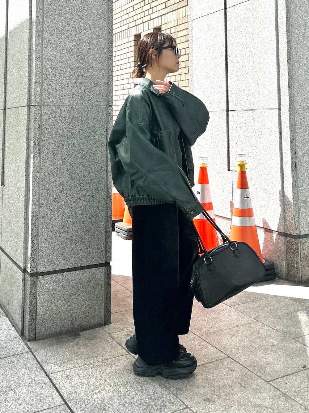 ブラック系のスニーカー、ブラック系のデニムパンツ、グリーン系のブルゾンを着用したレディースの秋コーディネートの4枚目の写真