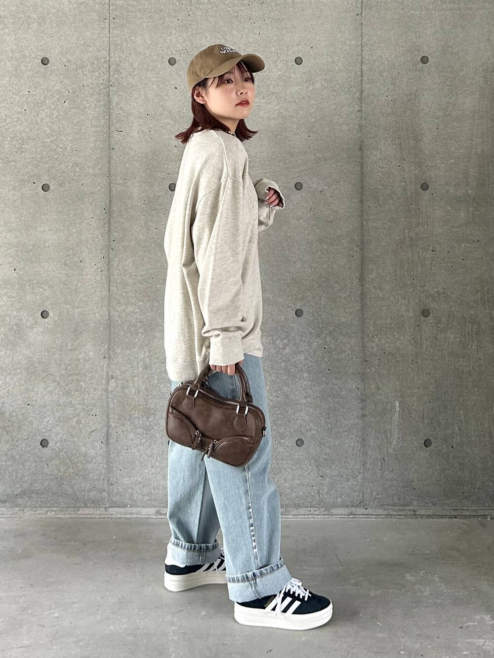 ベージュ系のスウェット、ブルー系のデニムパンツ、ブラック系のスニーカーを着用したレディースの春コーディネートの4枚目の写真