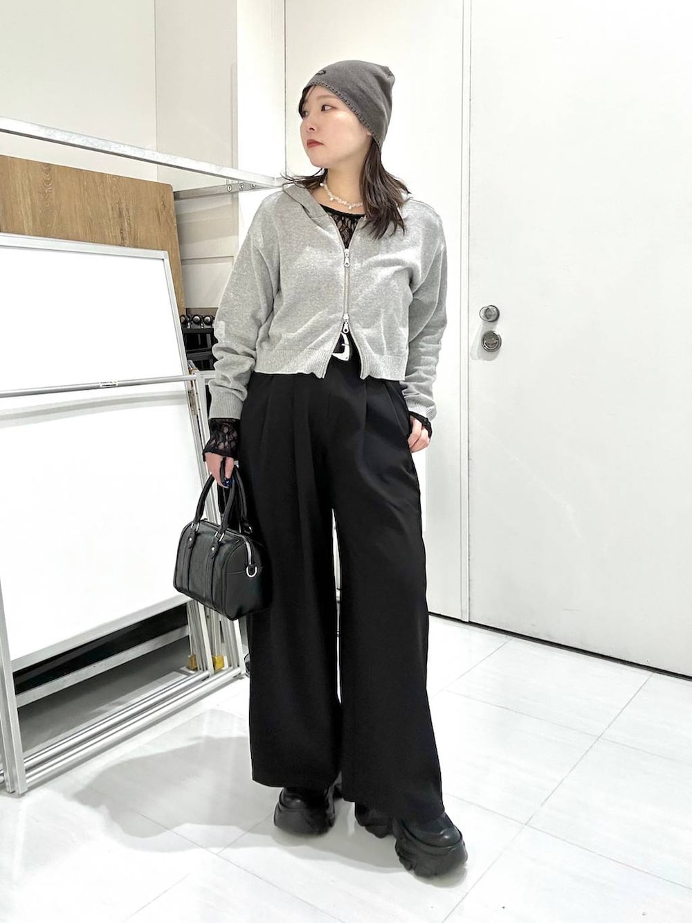 ブラック系のスニーカー、ブラック系のTシャツ/カットソー、ブラック系のボストンバッグを着用したレディースの冬コーディネートの2枚目の写真