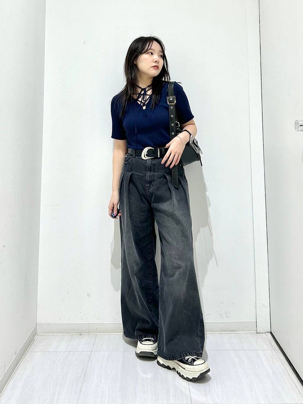 ブラック系のデニムパンツ、ブルー系のニット/セーター、ブラック系のベルトを着用したレディースの春コーディネートの3枚目の写真