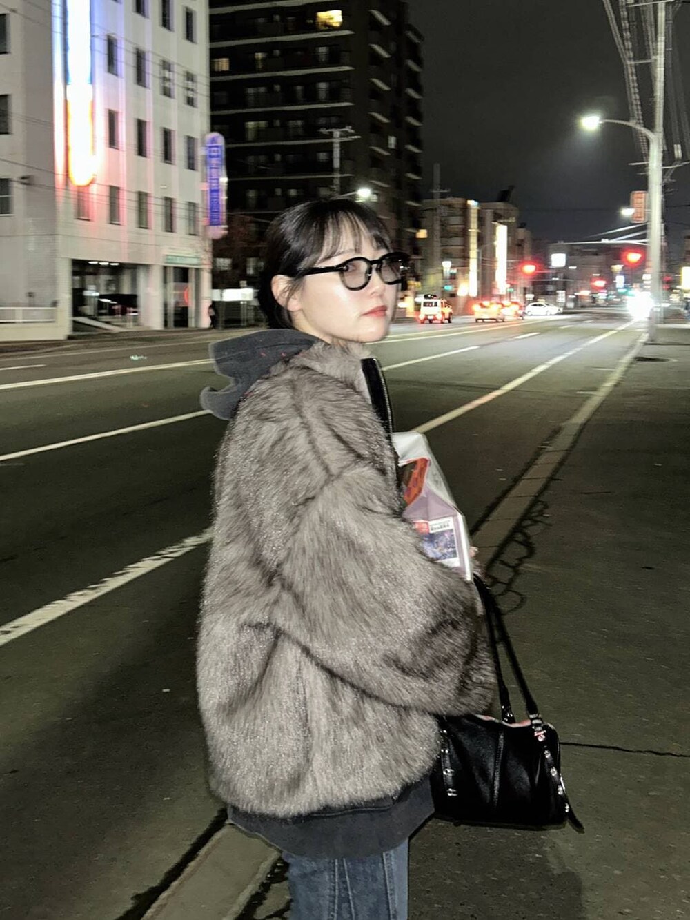 ブルー系のデニムパンツ、ブラック系のパーカー、ブラウン系のブルゾンを着用したレディースの秋コーディネートの4枚目の写真