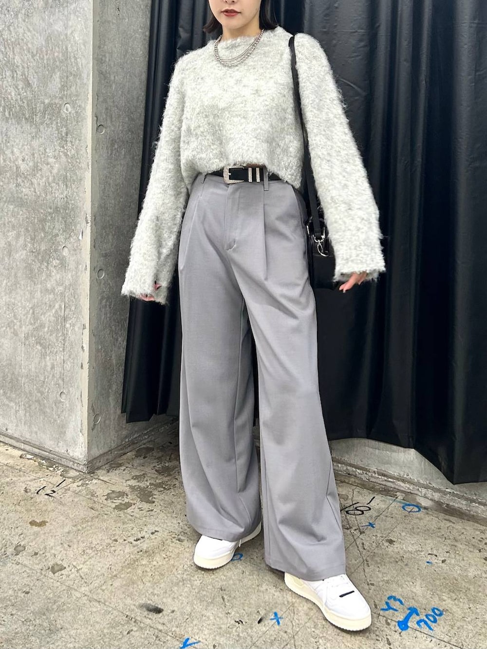 ホワイト系のスニーカー、グレー系のニット/セーター、ブラック系のベルトを着用したレディースの秋コーディネートの2枚目の写真