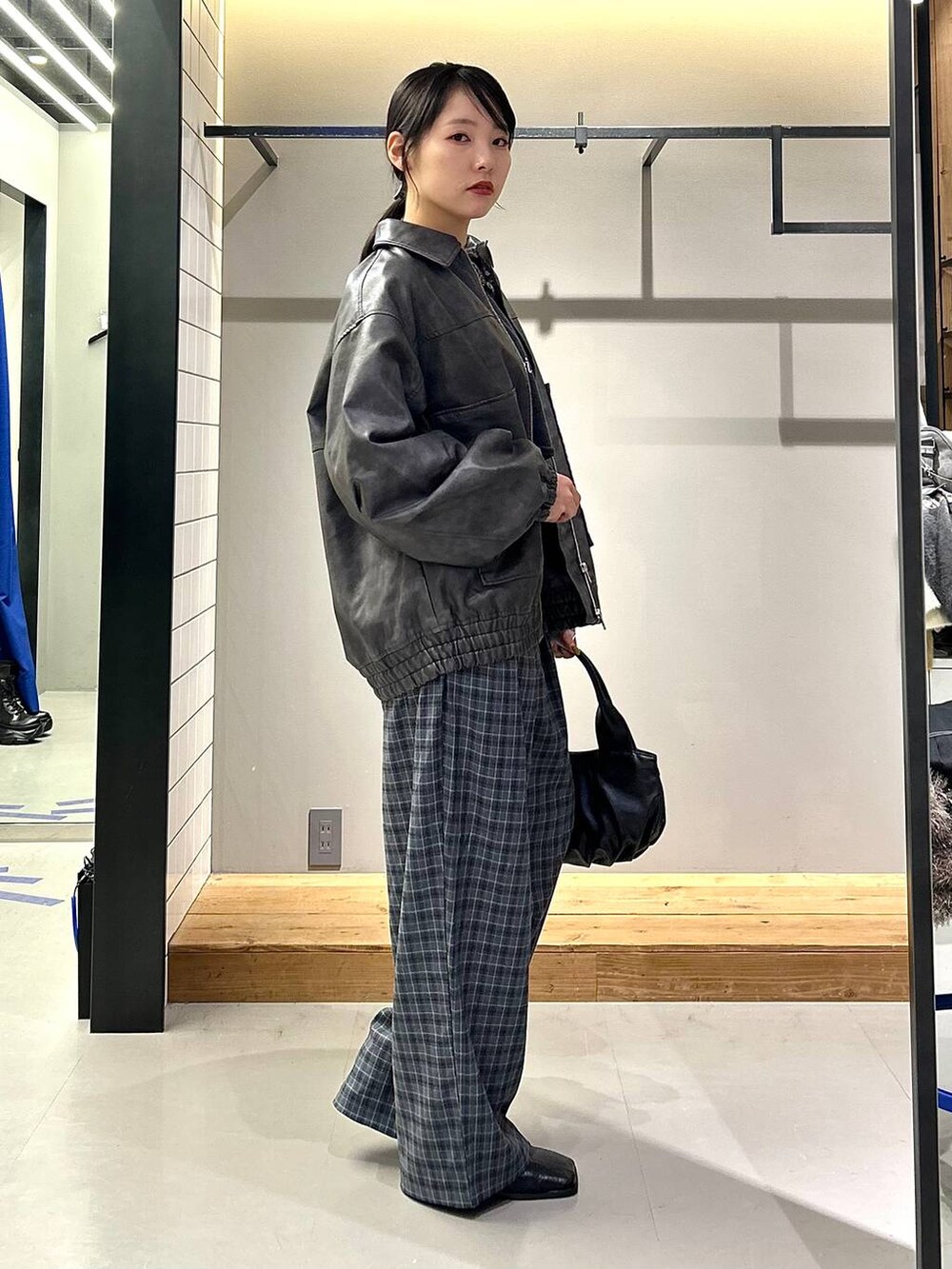 グレー系のブルゾン、ブラック系のブーツ、グレー系のスラックスを着用したレディースの秋コーディネートの4枚目の写真