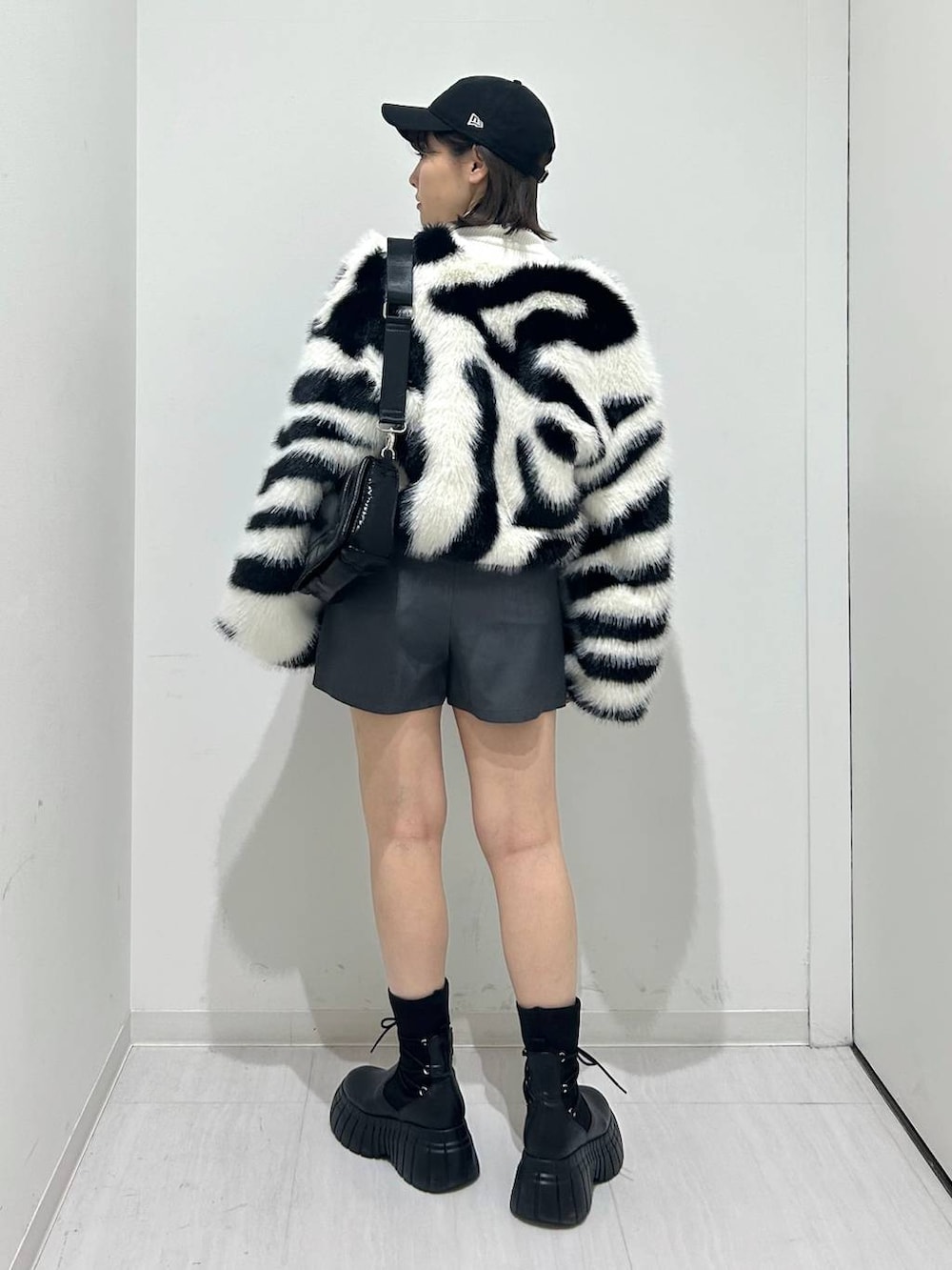 ホワイト系のニット/セーター、ブラック系のショルダーバッグ、ホワイト系のブルゾンを着用したレディースの秋コーディネートの5枚目の写真