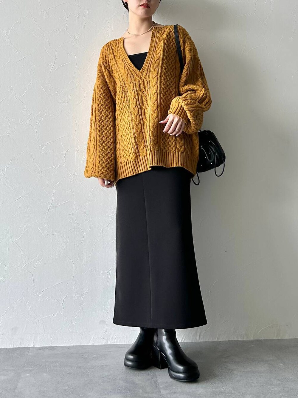 ブラック系のスカート、ブラック系のキャミソール、イエロー系のニット/セーターを着用したレディースの秋コーディネートの3枚目の写真