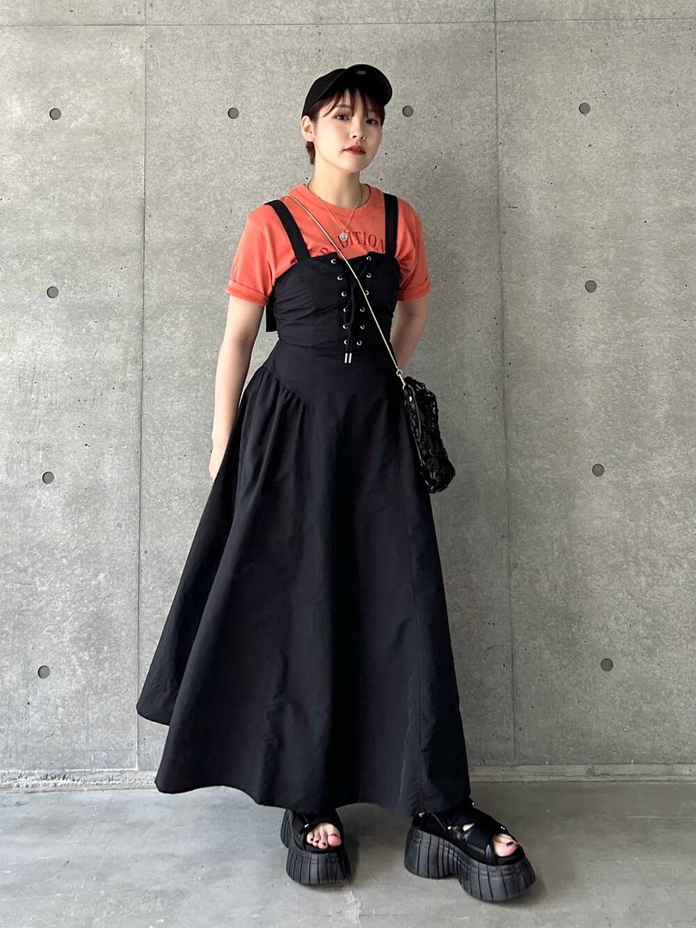 ブラック系のスニーカー、ブラック系のショルダーバッグ、ブラック系のワンピースを着用したレディースの夏コーディネートの2枚目の写真