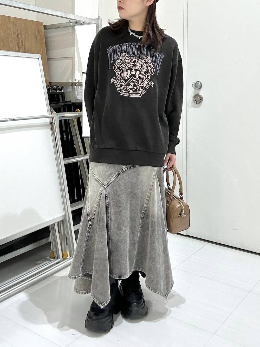 ブラック系のブーツ、グレー系のスウェット、ブラウン系のボストンバッグを着用したレディースの冬コーディネートの2枚目の写真