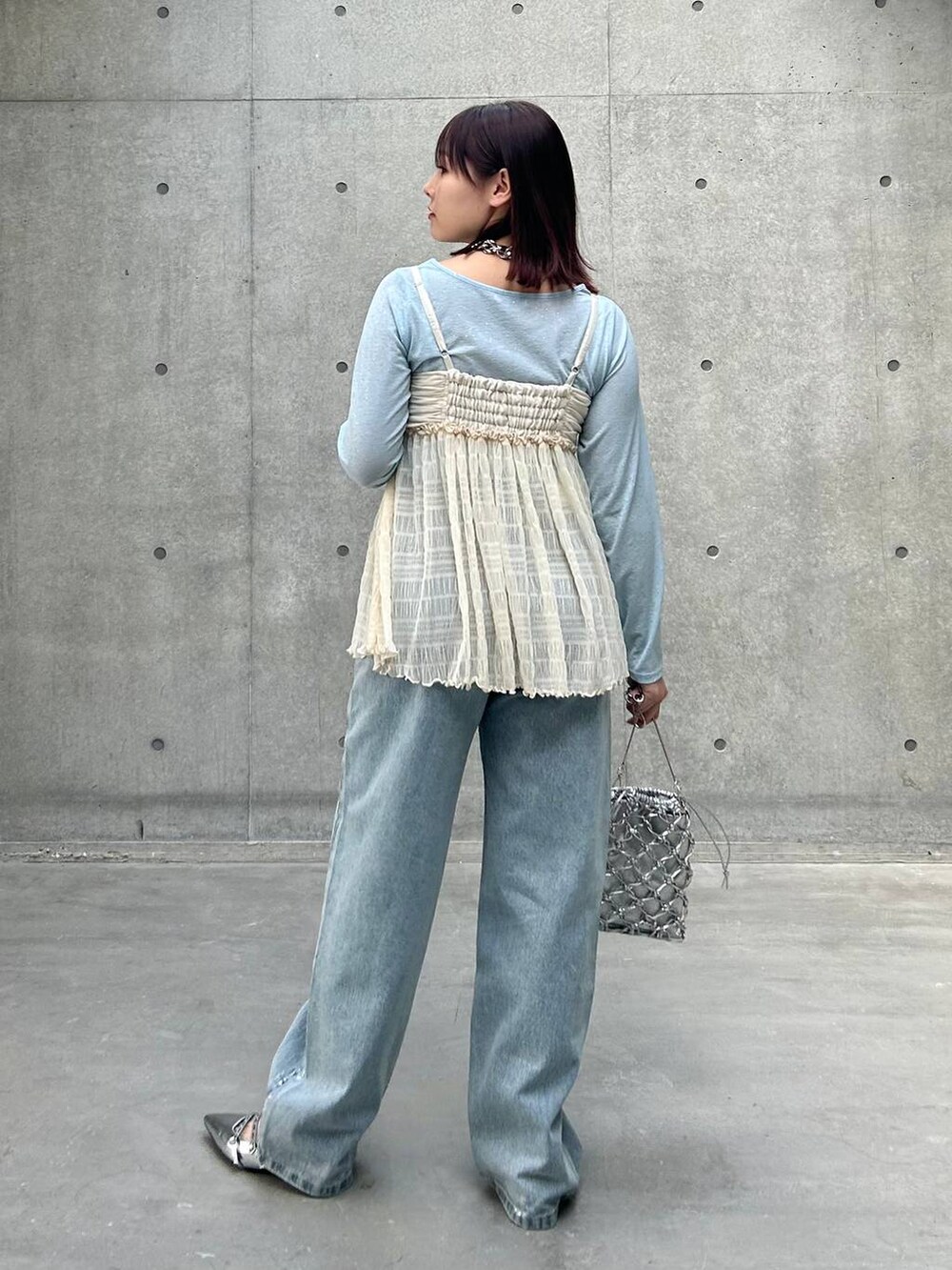 シルバー系のショルダーバッグ、ブルー系のデニムパンツ、ホワイト系のキャミソールを着用したレディースの春コーディネートの5枚目の写真