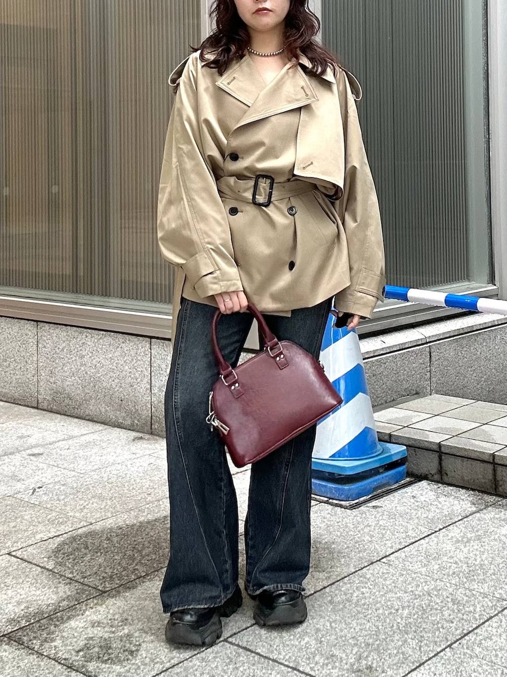 ブラック系のスニーカー、ブルー系のデニムパンツ、ベージュ系のトレンチコートを着用したレディースの秋コーディネートの5枚目の写真