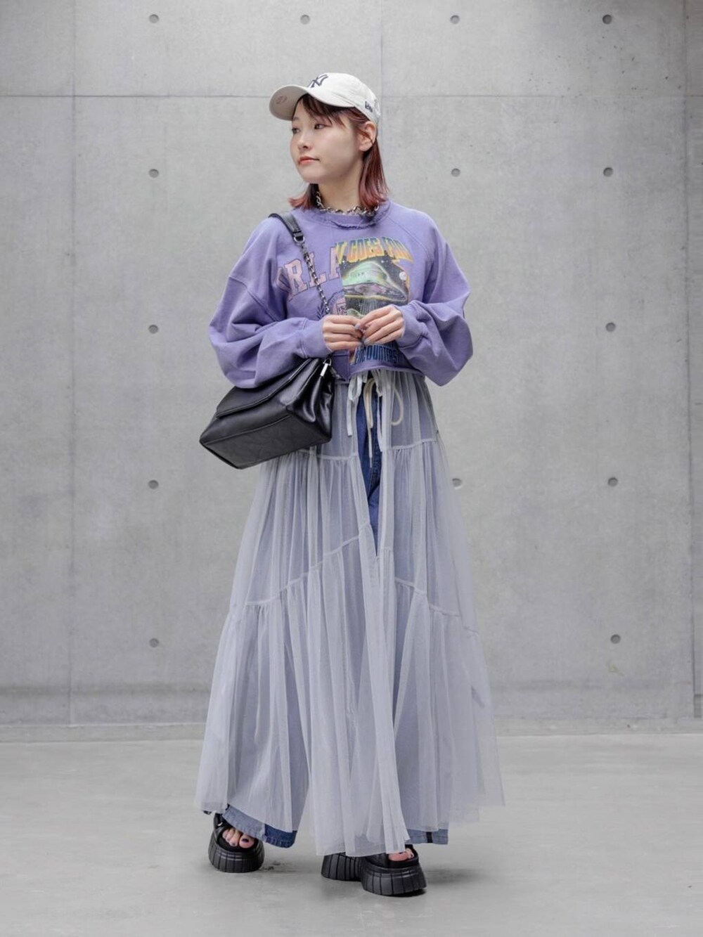 ベージュ系のスウェット、ホワイト系のワンピース、ブルー系のデニムパンツを着用したレディースの春コーディネートの2枚目の写真