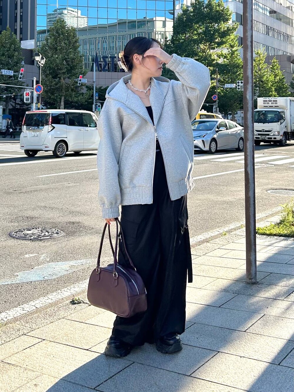 グレー系のパーカー、レッド系のボストンバッグ、ブラック系のスラックスを着用したレディースの秋コーディネートの9枚目の写真