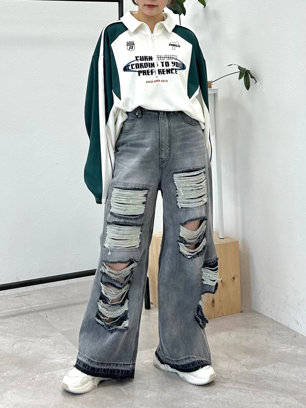 ホワイト系のポロシャツ、ブラック系のデニムパンツ、ブルー系のキャップを着用したレディースの冬コーディネートの3枚目の写真