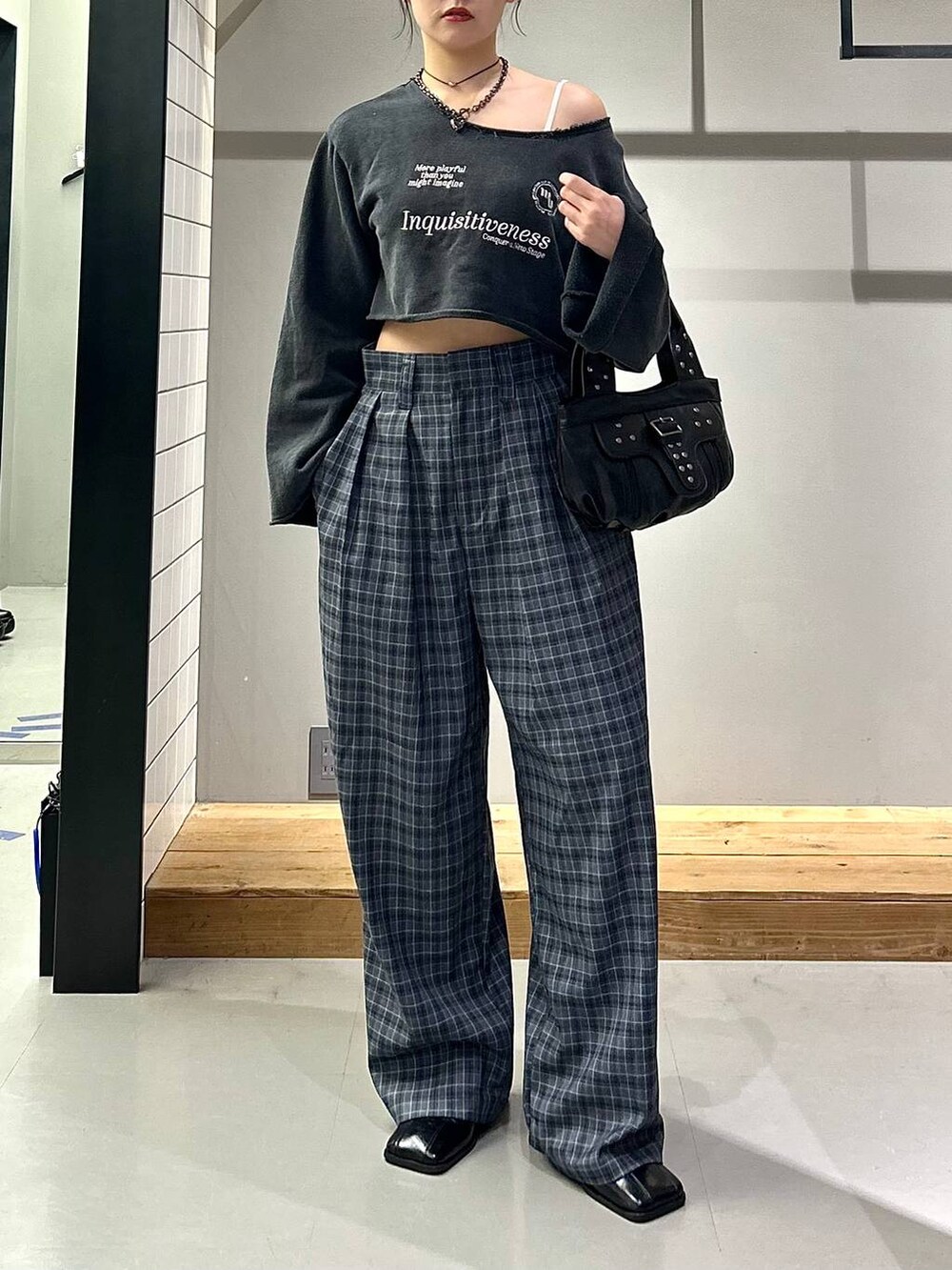 ブラック系のブーツ、グレー系のスラックス、ブラック系のハンドバッグを着用したレディースの秋コーディネートの2枚目の写真