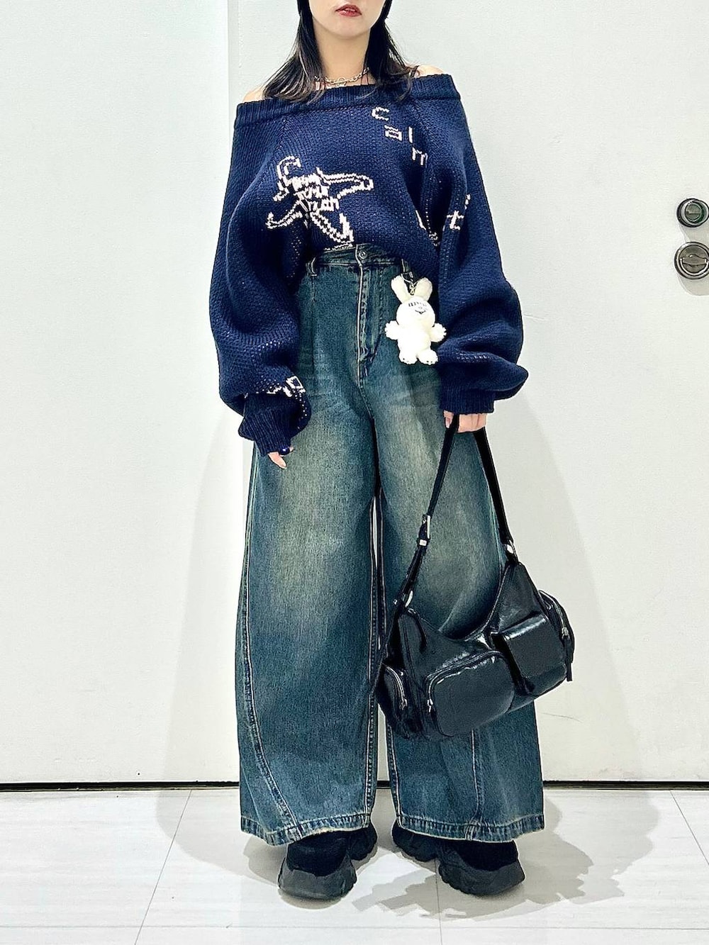 ブルー系のデニムパンツ、ブラック系のショルダーバッグ、ブルー系のニット/セーターを着用したレディースの秋コーディネートの3枚目の写真