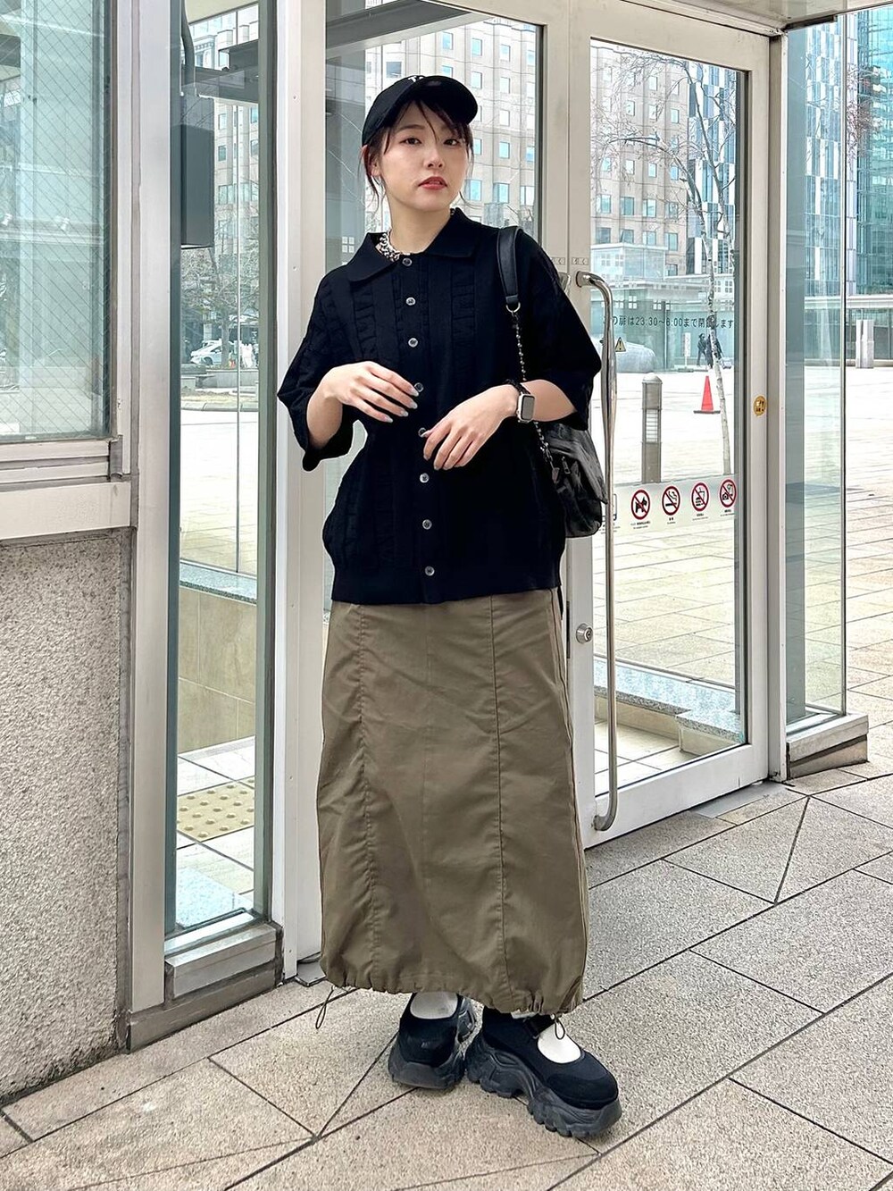 ブラック系のショルダーバッグ、グリーン系のスカート、ブラック系のニット/セーターを着用したレディースの春コーディネートの4枚目の写真