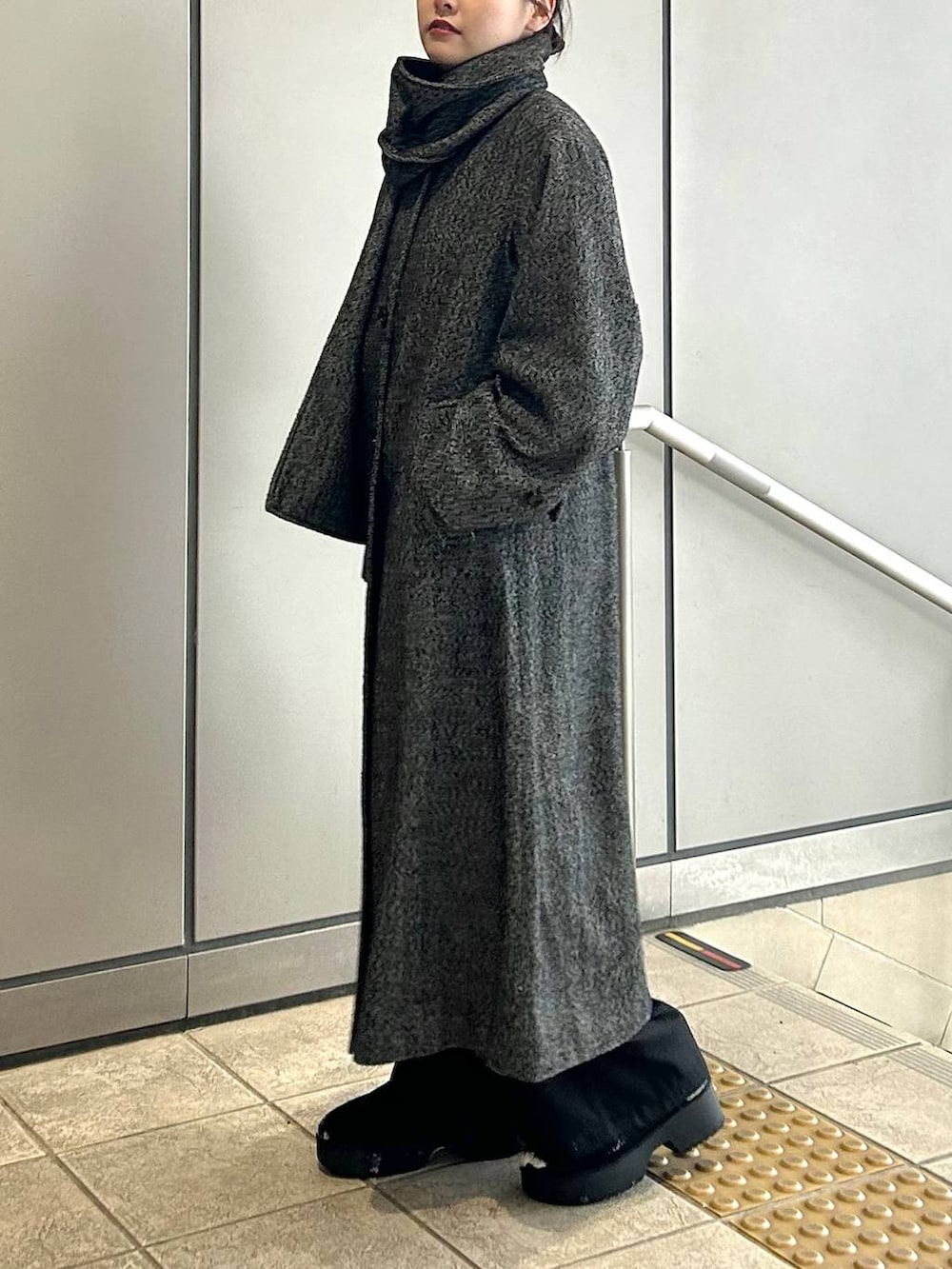 ブラック系のチェスターコート、ブラック系のスラックス、ブラック系のショルダーバッグを着用したレディースの冬コーディネートの6枚目の写真