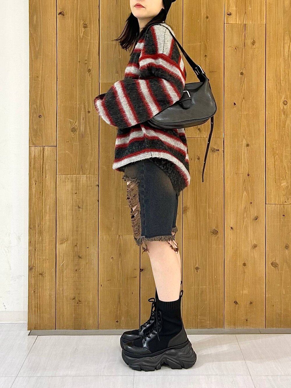 ブラック系のショルダーバッグ、ブラック系のブーツ、レッド系のニット/セーターを着用したレディースの秋コーディネートの7枚目の写真