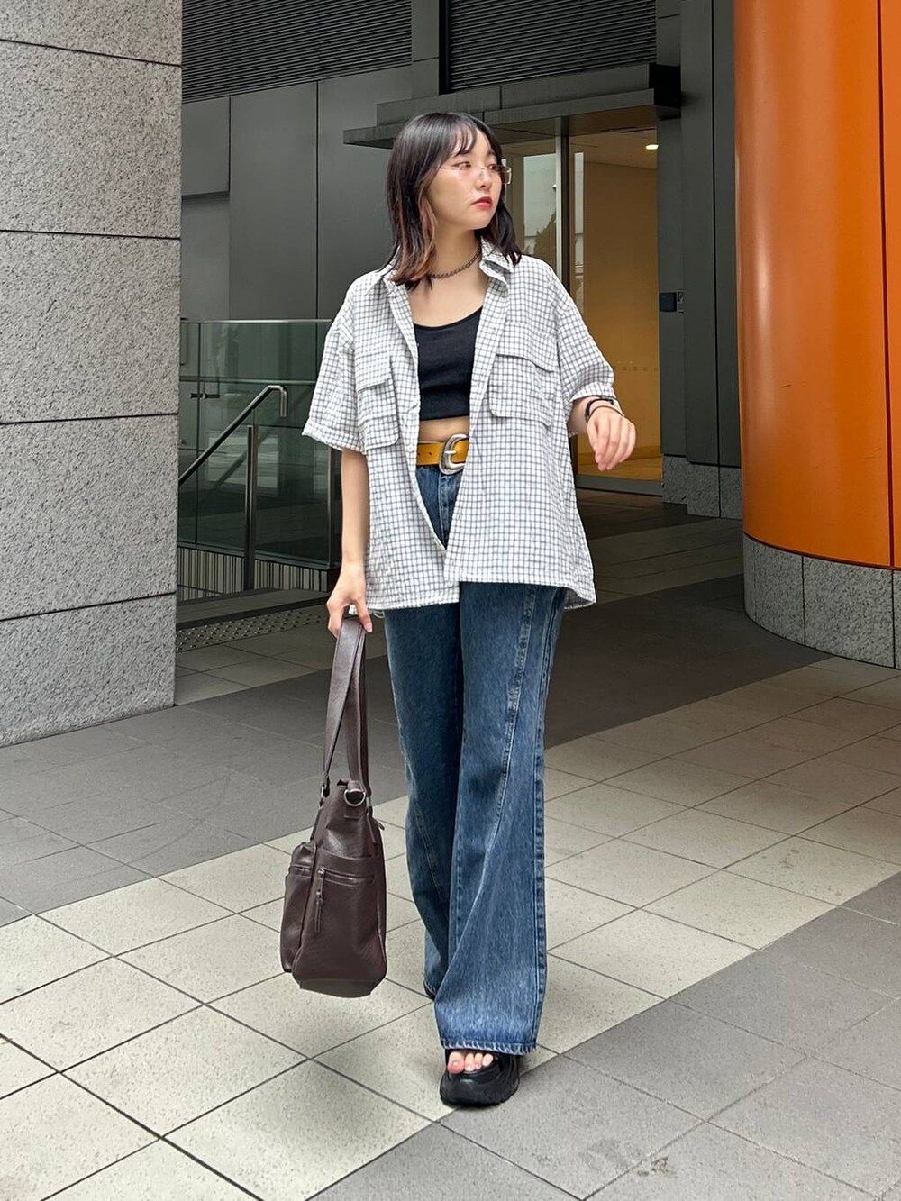 ブルー系のデニムパンツ、ホワイト系のシャツ/ブラウス、ブラック系のボストンバッグを着用したレディースの夏コーディネートの2枚目の写真