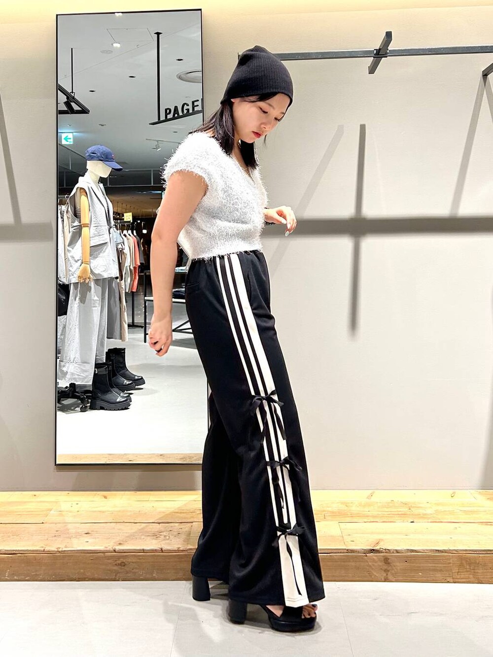 ブラック系のサンダル、ホワイト系のベスト、ブラック系のキャミソールを着用したレディースの夏コーディネートの4枚目の写真