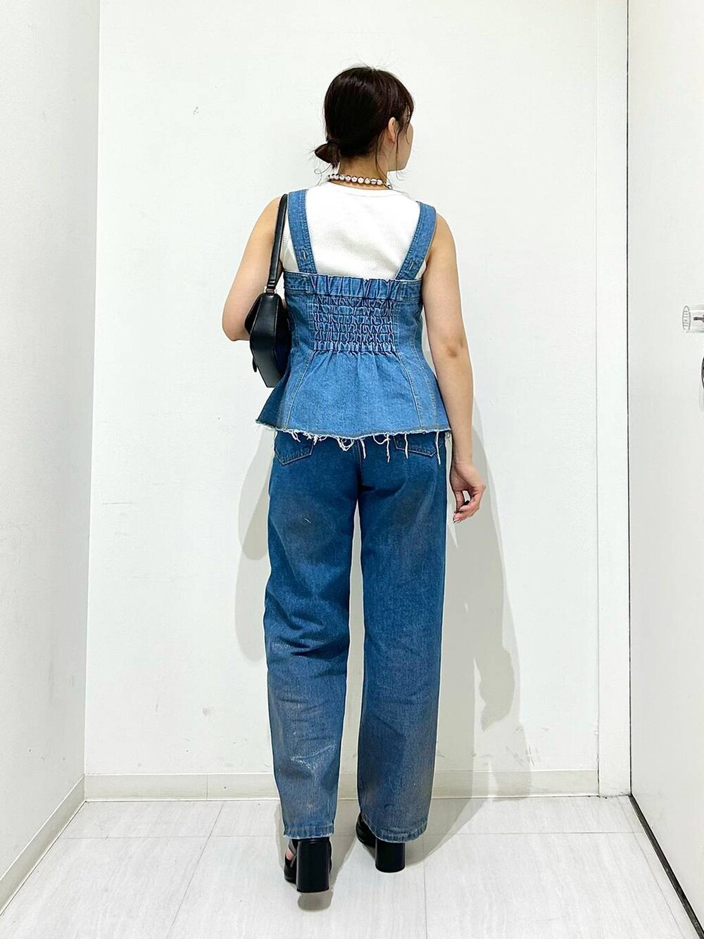 ブラック系のサンダル、ブラック系のハンドバッグ、ホワイト系のタンクトップを着用したレディースの夏コーディネートの4枚目の写真