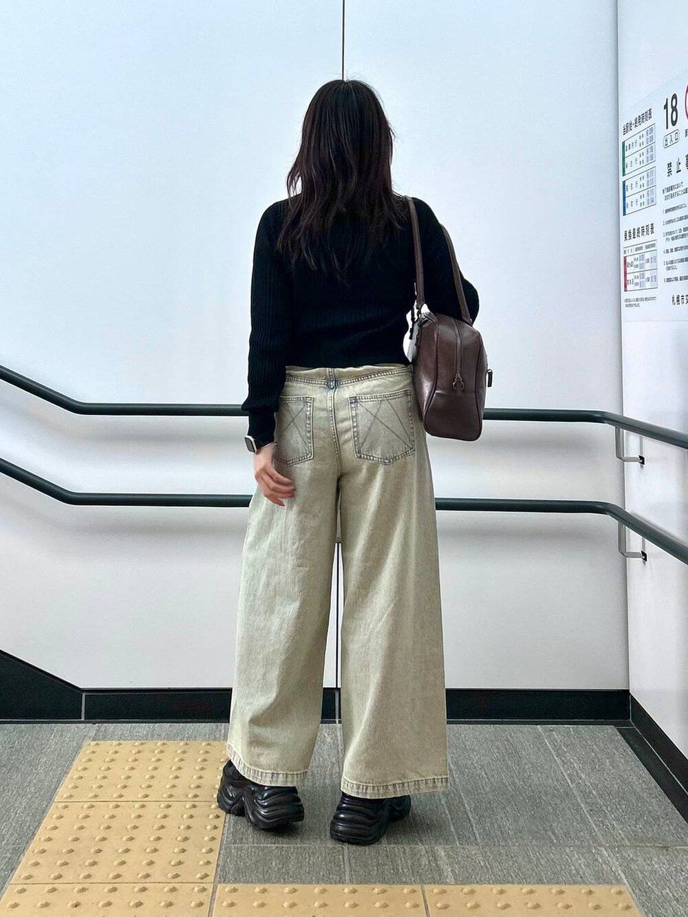 ブラック系のスニーカー、ブルー系のデニムパンツ、ブラウン系のボストンバッグを着用したレディースの夏コーディネートの6枚目の写真