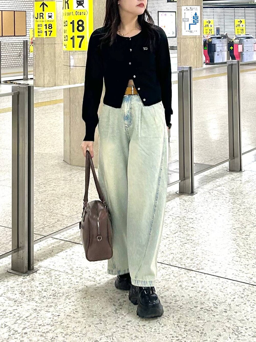 ブラック系のスニーカー、ブルー系のデニムパンツ、ブラウン系のボストンバッグを着用したレディースの夏コーディネートの2枚目の写真