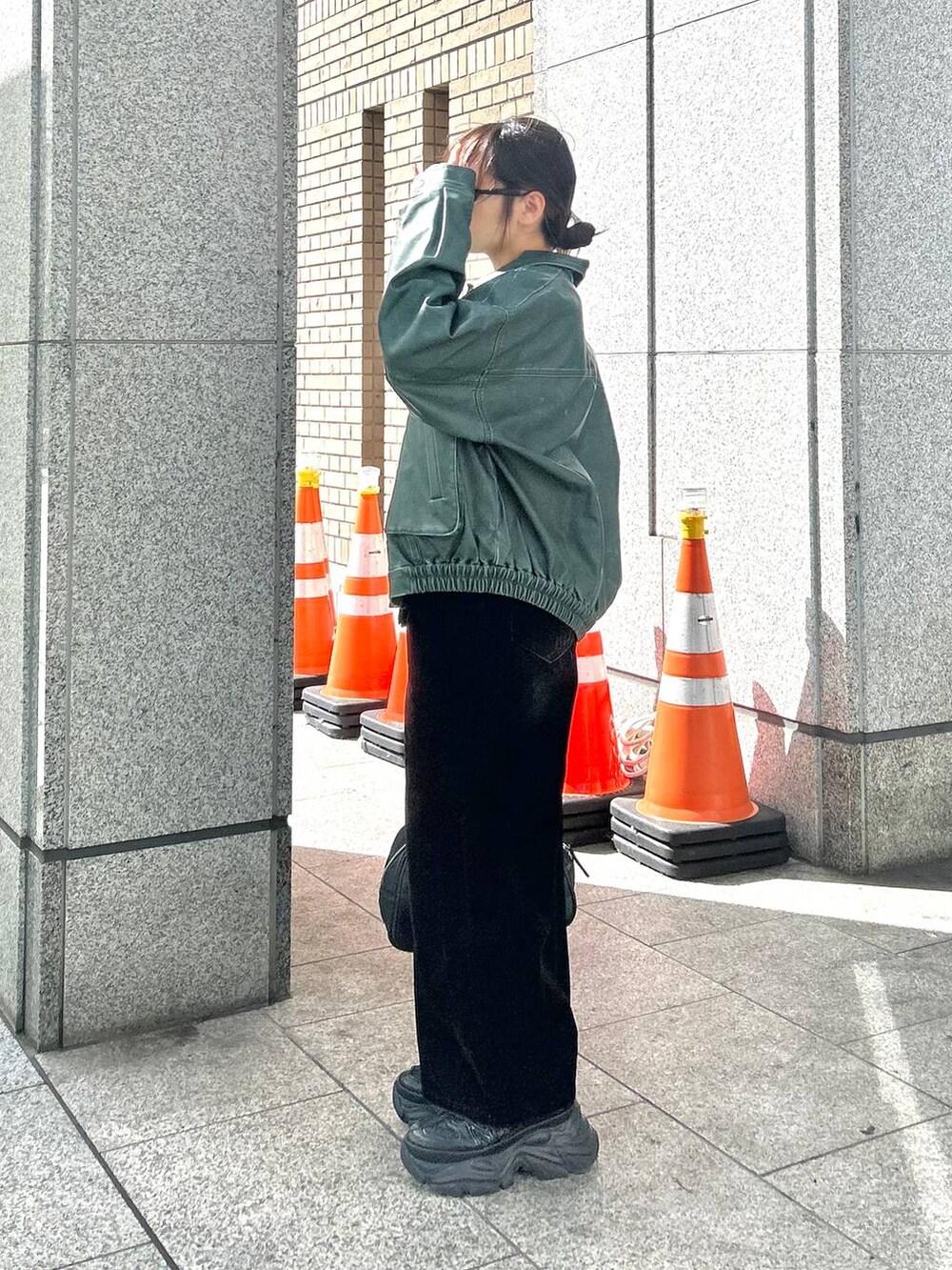 ブラック系のスニーカー、ブラック系のデニムパンツ、グリーン系のブルゾンを着用したレディースの秋コーディネートの3枚目の写真