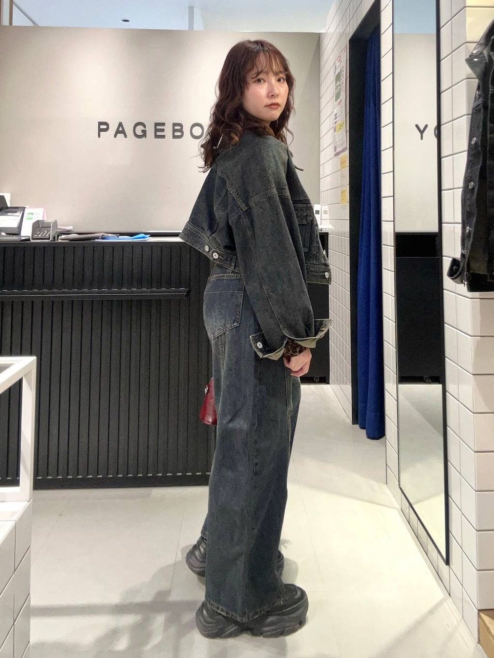 ブルー系のデニムパンツ、ブラック系のスニーカー、ブルー系のデニムジャケットを着用したレディースの秋コーディネートの3枚目の写真