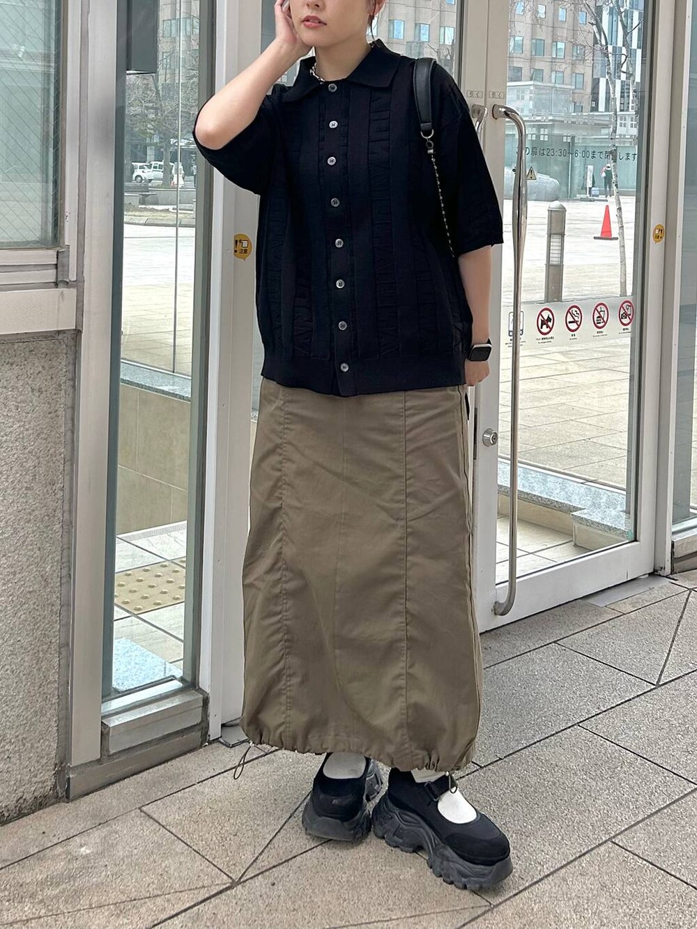 ブラック系のショルダーバッグ、グリーン系のスカート、ブラック系のニット/セーターを着用したレディースの春コーディネートの5枚目の写真