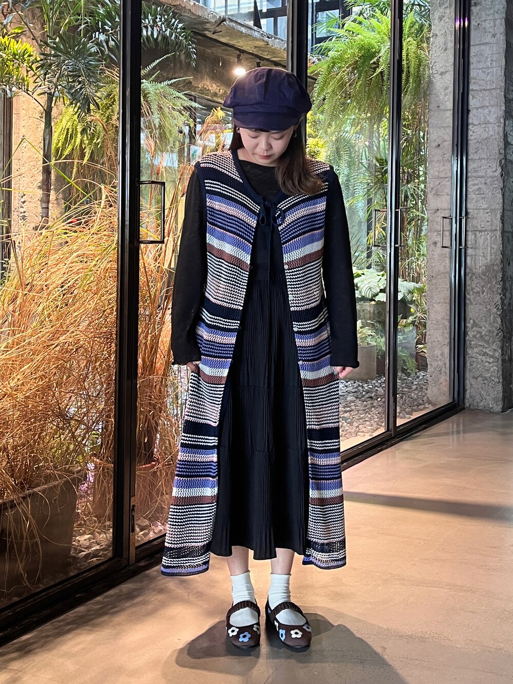 ブラック系のベスト、ブラウン系のシューズ、ブルー系のキャップを着用したレディースの夏コーディネートの2枚目の写真