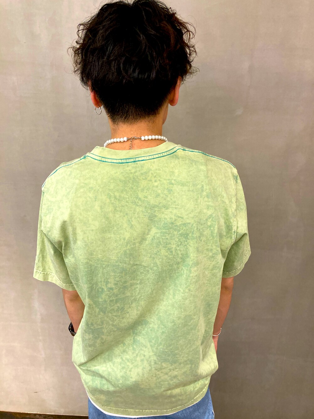 ブルー系のデニムパンツ、ホワイト系のスニーカー、グリーン系のTシャツ/カットソーを着用したメンズの夏コーディネートの2枚目の写真