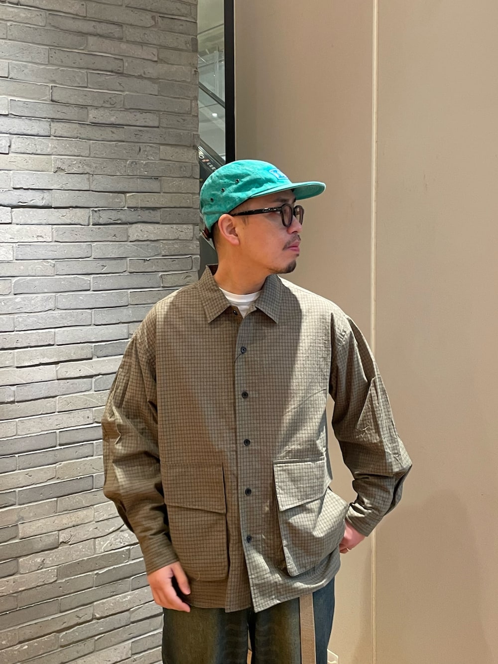 グリーン系のシャツ/ブラウス、ブルー系のデニムパンツを着用したメンズの春コーディネートの2枚目の写真