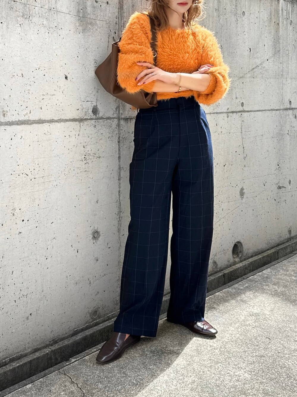 オレンジ系のニット/セーター、ブルー系のパンツ、ブラウン系のバッグを着用したレディースの秋コーディネートの2枚目の写真