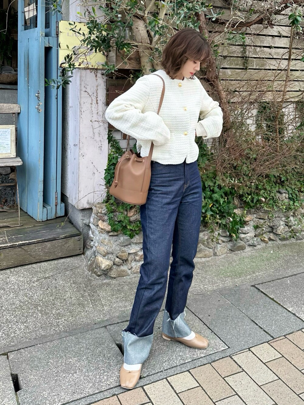 ホワイト系のノーカラージャケット、ブルー系のデニムパンツ、ホワイト系のトップスを着用したレディースの冬コーディネートの2枚目の写真