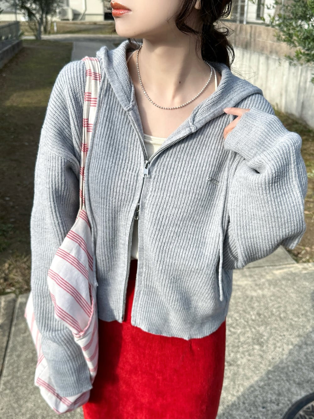 グレー系のパーカー、レッド系のスカート、ベージュ系のスニーカーを着用したレディースの冬コーディネートの4枚目の写真