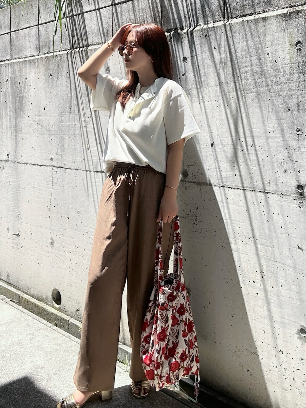 ホワイト系のTシャツ/カットソー、ブラウン系のスラックス、ゴールド系のサンダルを着用したレディースの夏コーディネートの4枚目の写真