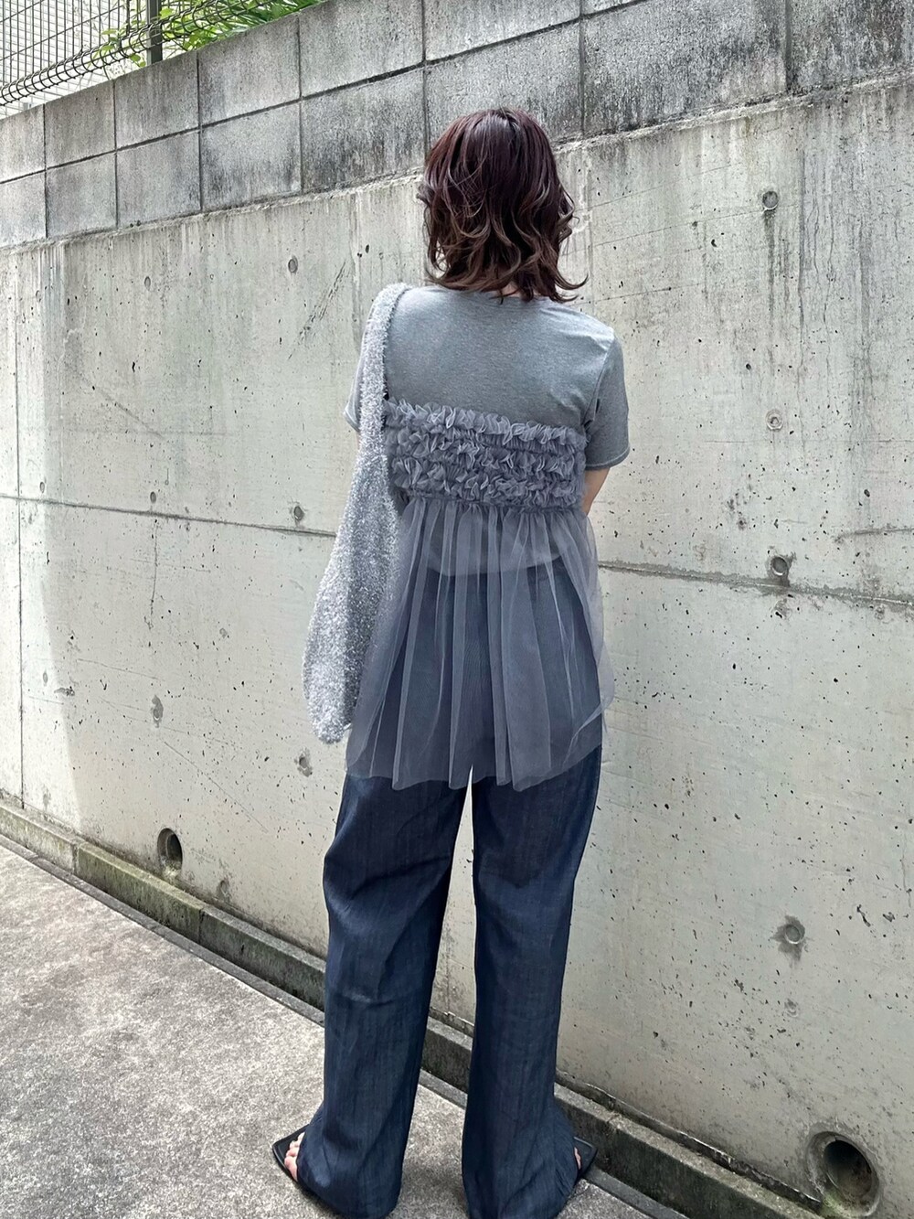 グレー系のTシャツ/カットソー、シルバー系のショルダーバッグ、ブルー系のデニムパンツを着用したレディースの夏コーディネートの3枚目の写真